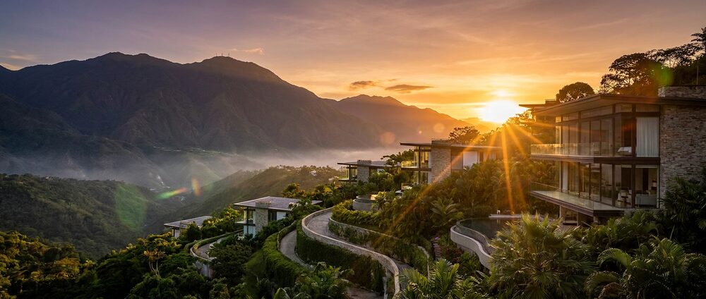 Terraced hillside houses at sunset, looking out across a forested valley