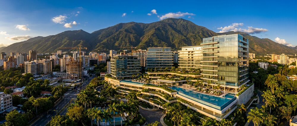 Glass residential towers above landscaped terraces in Caracas, with the Avila mountain rising behind the city